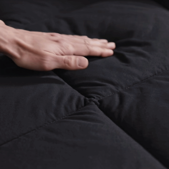A hand pressing into the soft fill of a black 2-in-1 Comforter