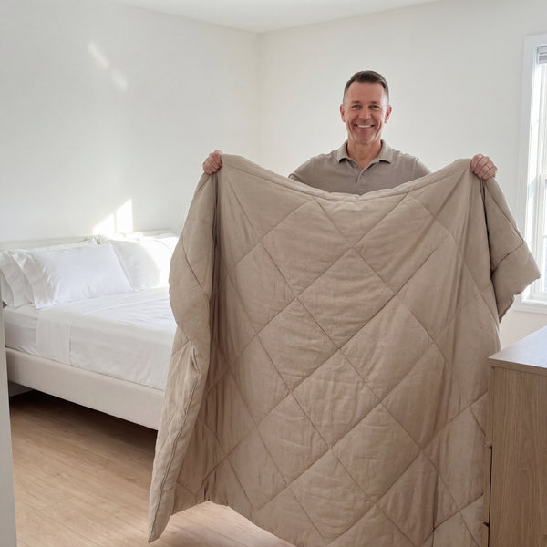 A customer holding up a beige 2-in-1 Comforter in a bright bedroom