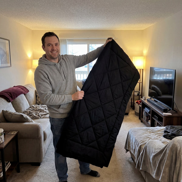 A customer holding up a black 2-in-1 Comforter at home